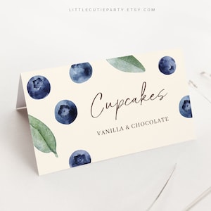 May include: A light beige card with a watercolor design of blueberries and leaves. The card says "Cupcakes" in brown cursive writing and "Vanilla & Chocolate" in brown text.