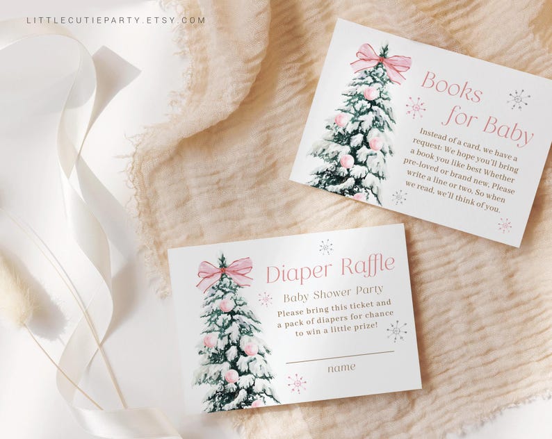 May include: Two baby shower cards with a watercolor Christmas tree design. One card reads "Books for Baby" and the other says "Diaper Raffle". Both cards have pink bows and snowflakes. The cards are on a cream-colored surface.