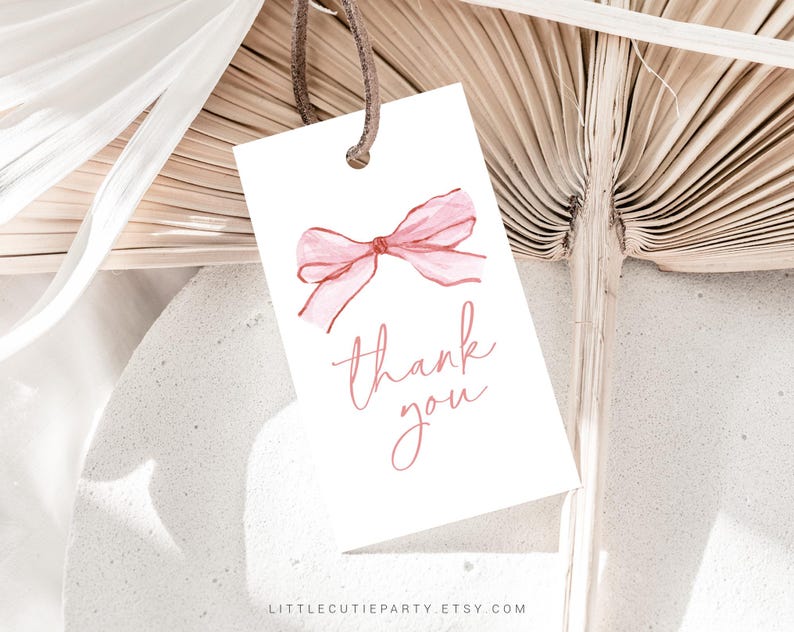May include: A white gift tag with a watercolor-style pink bow and the words "thank you" in a delicate script. The tag is suspended by a brown string, perfect for adding a personal touch to gifts.