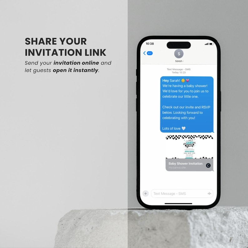 May include: A smartphone displays a baby shower invitation. The screen shows a text message with an invitation and a link. The text reads "Hey Sarah! We're having a baby shower!" and "Baby Shower Invitation". The phone is on a light gray surface.