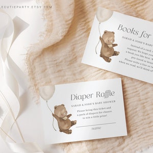May include: Two printable cards for a baby shower. The top card features a brown bear holding a balloon and the text "Books for Baby". The bottom card features a brown bear holding a balloon and the text "Diaper Raffle".