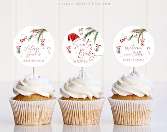 Könnte beinhalten: Drei Cupcakes mit weißem Zuckerguss, jeweils mit einem runden Papieraufsatz. Die Aufsätze zeigen festliche Designs mit Text für eine Babyparty. Einer sagt "Victoria + Josh's BABY SHOWER", ein anderer "Santa Baby SHOWER" und der letzte "Welcome our little BABY JACKSON".