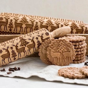 May include: A wooden rolling pin with a Christmas-themed design featuring reindeer and Christmas trees. The rolling pin is used to create decorative patterns on cookies. A stack of cookies with the same design is shown in the image.