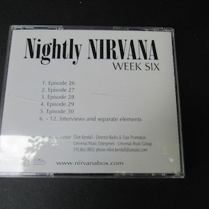May include: A CD case with the text "Nightly NIRVANA WEEK SIX" in black font. The track list includes episodes 26-30 and interviews. The website www.nirvanabox.com is also visible.