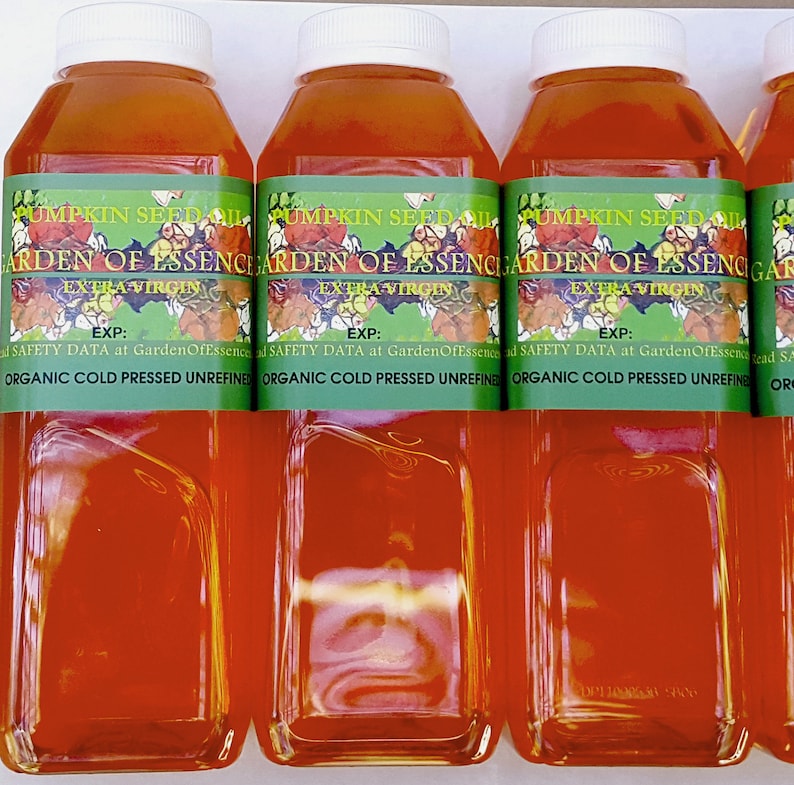 Puede incluir: Varias botellas de pl&aacute;stico transparente llenas de l&iacute;quido naranja, cada una con una tapa blanca. Las botellas tienen etiquetas verdes con el texto "PUMPKIN SEED OIL GARDEN OF ESSENCE EXTRA VIRGIN". Las etiquetas tambi&eacute;n incluyen el texto "ORGANIC COLD PRESSED UNREFINED".