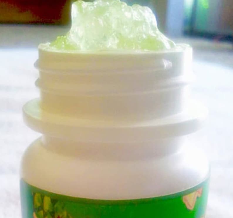 May include: A white plastic jar with a green label and a clear lid. The jar is filled with a green gel-like substance.