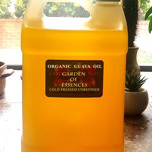 May include: A large, translucent yellow plastic jug filled with organic guava oil. The jug has a handle and a gray cap. A label on the front reads "Organic Guava Oil" and "Cold Pressed Unrefined."