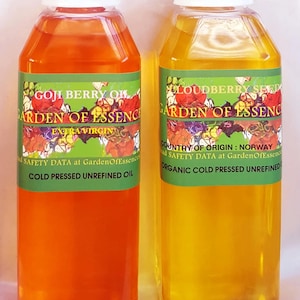 Puede incluir: Dos botellas de pl&aacute;stico transparente llenas de aceite naranja y amarillo. Las botellas tienen tapas blancas y etiquetas verdes con dise&ntilde;os florales y texto que dice "GOJI BERRY OIL" y "LOUDBERRY SEED". Las etiquetas tambi&eacute;n indican "COLD PRESSED UNREFINED OIL".