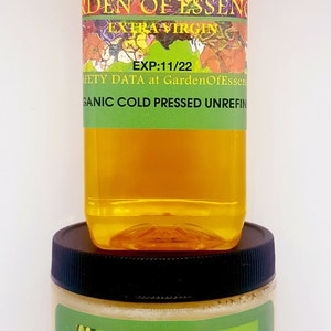 May include: Two bottles of organic cold-pressed jojoba oil and butter from Garden of Essences. The oil bottle is clear with a green label that says "Jojoba Oil Garden of Essences Extra Virgin EXP:11/22 Safety Data at GardenOfEssences.com Organic Cold Pressed Unrefined". The butter jar is white with a green label that says "Jojoba Butter Garden of Essences RAW and UNREFINED GARDENOFESSENCES on etsy.com Read Safety Data at GardenOfEssences.com Organic Cold Pressed".