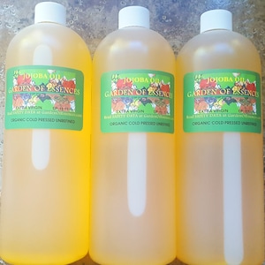May include: Three amber glass bottles of jojoba oil labeled "Jojoba Oil Garden of Essences Extra Virgin Organic Cold Pressed Unrefined" with the text "EP:11 11" on each label.