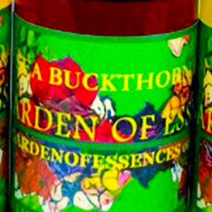 May include: A glass bottle with a green label that reads "A Buckthorn Garden of Essences" and "Organic Unrefined Cold Pressed Oil". The bottle contains a dark red liquid.