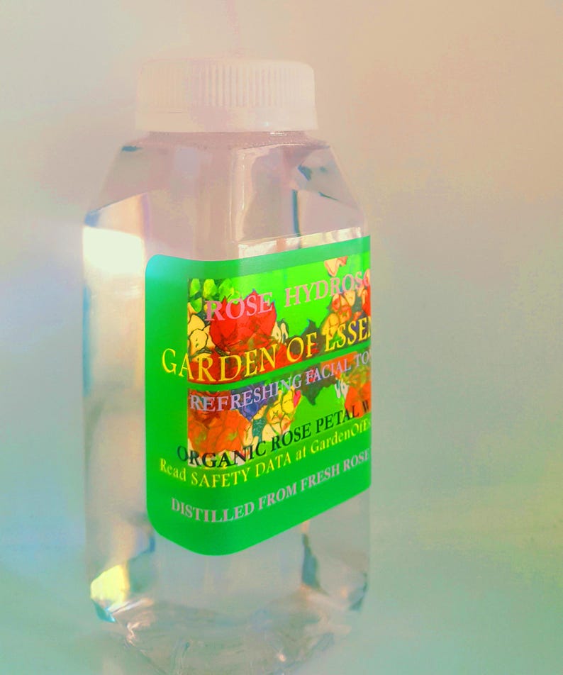 K&ouml;nnte beinhalten: Eine klare Glasflasche mit wei&szlig;em Verschluss, gef&uuml;llt mit einer klaren Fl&uuml;ssigkeit. Die Flasche hat ein gr&uuml;nes Etikett mit dem Text "ROSE HYDROS GARDEN OF ESSENCE REFRESHING FACIAL TONER ORGANIC ROSE PETAL WATER Read SAFETY DATA at GardenOfDistilled FROM FRESH ROSE"