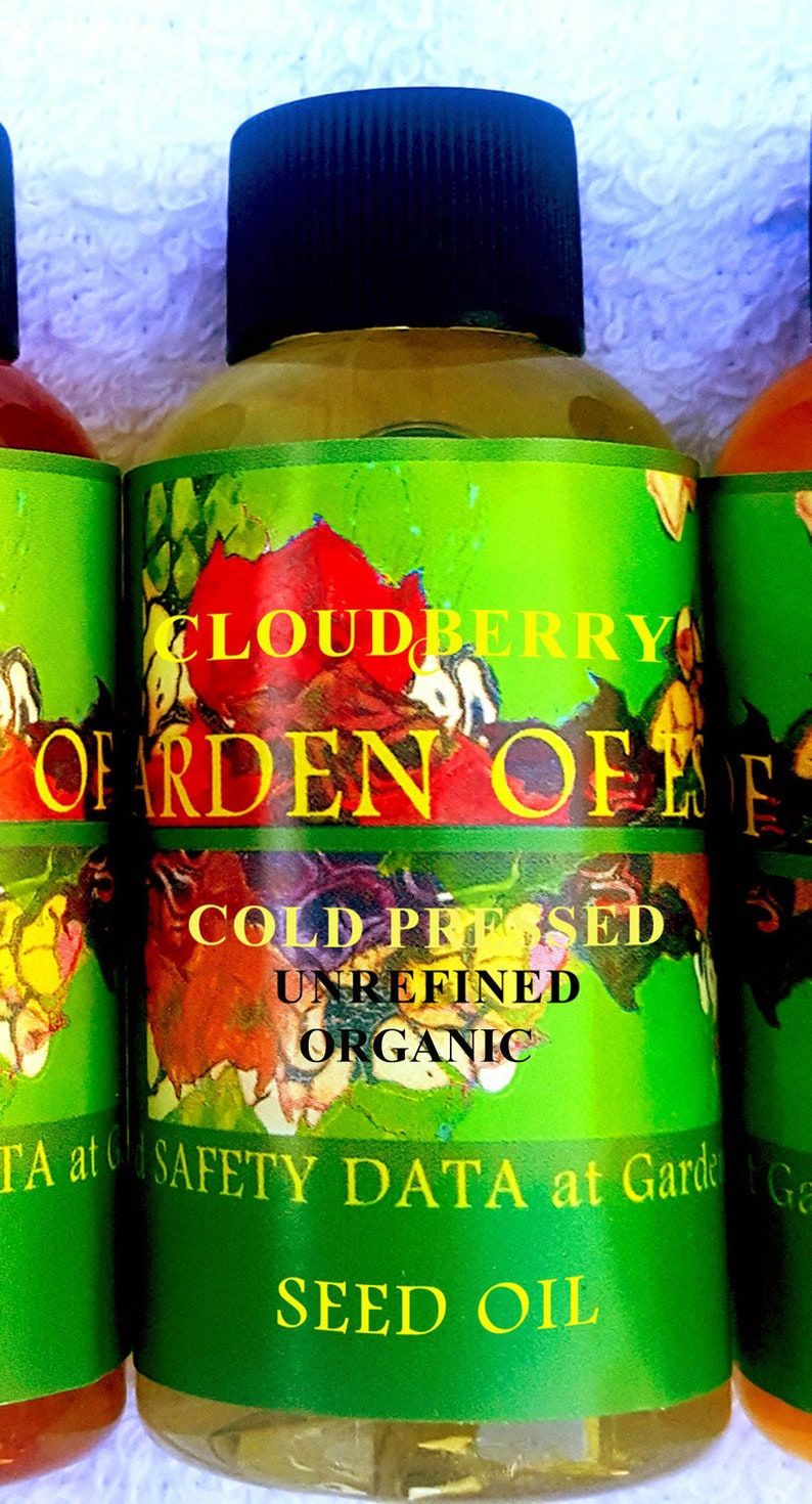 Puede incluir: Botellas de aceite de semillas Cloudberry Garden of Eden. Las etiquetas son verdes con dise&ntilde;os florales coloridos y el texto "Cloudberry", "Cold Pressed", "Unrefined" y "Organic". Las botellas tienen tapas negras.