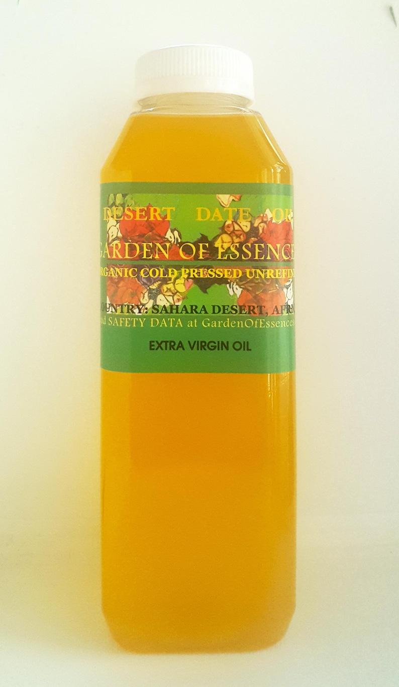 May include: A clear glass bottle with a white cap filled with a yellow liquid. The label reads "Desert Date Oil Garden of Essence Organic Cold Pressed Unrefined" and "Country: Sahara Desert, Africa" and "Safety Data at GardenOfEssence.com" and "Extra Virgin Oil".