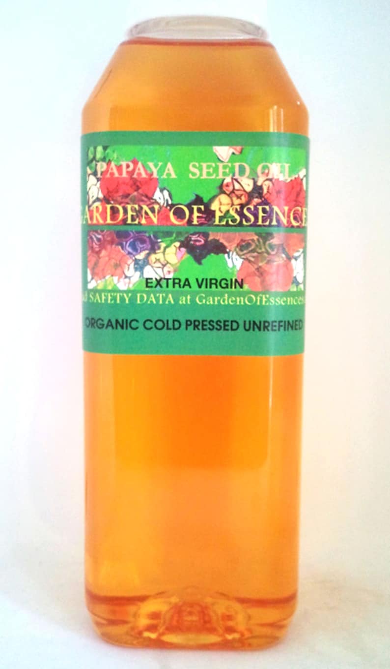 K&ouml;nnte beinhalten: Eine durchsichtige Kunststoffflasche gef&uuml;llt mit orangefarbenem Papayasamen&ouml;l. Das gr&uuml;ne Etikett tr&auml;gt den Text PAPAYA SEED OIL, GARDEN OF ESSENCE, EXTRA VIRGIN und ORGANIC COLD PRESSED UNREFINED sowie ein buntes florales Grafikdesign.