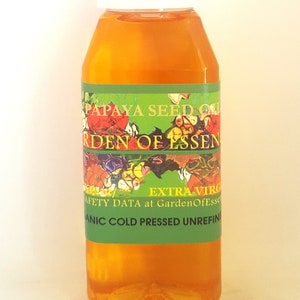 K&ouml;nnte beinhalten: Eine durchsichtige Kunststoffflasche gef&uuml;llt mit gold-orangem Papayasamen&ouml;l. Das Etikett hat einen gr&uuml;nen Hintergrund mit einer Blumenillustration und dem Text PAPAYA SEED OIL, GARDEN OF ESSENCE, EXTRA VIRGIN, ORGANIC COLD PRESSED UNREFINED.