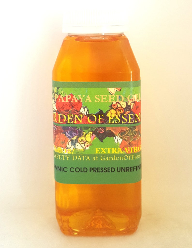 K&ouml;nnte beinhalten: Eine durchsichtige Kunststoffflasche gef&uuml;llt mit gold-orangem Papayasamen&ouml;l. Das Etikett hat einen gr&uuml;nen Hintergrund mit einer Blumenillustration und dem Text PAPAYA SEED OIL, GARDEN OF ESSENCE, EXTRA VIRGIN, ORGANIC COLD PRESSED UNREFINED.