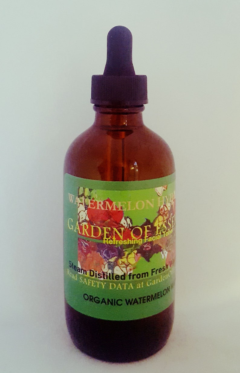 May include: A brown glass bottle with a black dropper top. The label reads "WATERMELON HYDRATE GARDEN OF ESSENCE Refreshing Facial Toner". The label is green with floral illustrations and text. The bottle contains a clear liquid.
