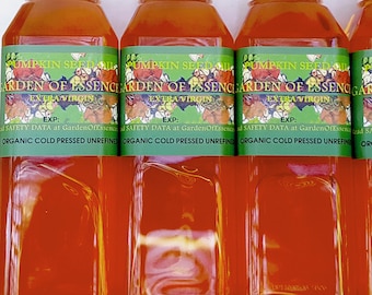 Könnte beinhalten: Transparente Kunststoffflaschen gefüllt mit bernsteinfarbenem Kürbiskernöl. Jede Flasche hat ein grünes Etikett mit dem Text PUMPKIN SEED OIL, GARDEN OF ESSENCE, EXTRA VIRGIN, EXP und ORGANIC COLD PRESSED UNREFINED sowie einem Blumenmotiv.