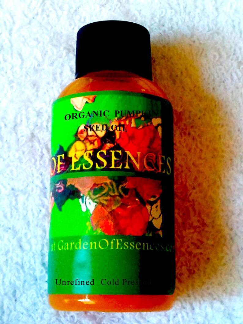 Puede incluir: Una botella de aceite de semilla de calabaza org&aacute;nico con tapa negra. La etiqueta verde tiene las palabras "Organic Pumpkin Seed Oil" y "Garden Of Essences". La parte inferior de la etiqueta dice "Unrefined Cold Pressed".