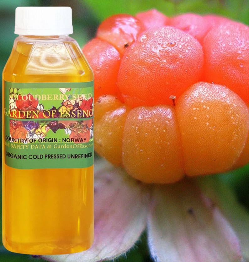 Puede incluir: Una botella transparente con tapa blanca y etiqueta verde. La etiqueta dice "LOUDBERRY SEED GARDEN OF ESSENCE" y "ORGANIC COLD PRESSED UNREFINED." Junto a la botella, varias bayas de los pantanos de color naranja.