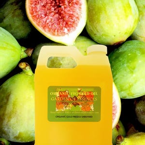 May include: A yellow container of organic fig seed oil with a green label that reads "ORGANIC FIG SEED OIL GARDEN OF ESSENCES". The container is surrounded by fresh figs, some halved to reveal their red interior.