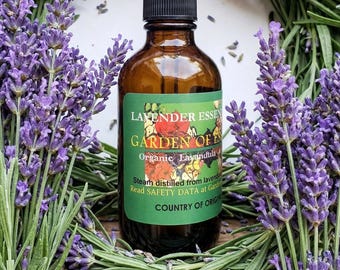 May include: An amber glass dropper bottle with a black cap and a green label featuring the text Lavender Essen, Garden of Eden, Organic Lavandula, Steam distilled from lavender, Read SAFETY DATA at Garden, Country of Origin.