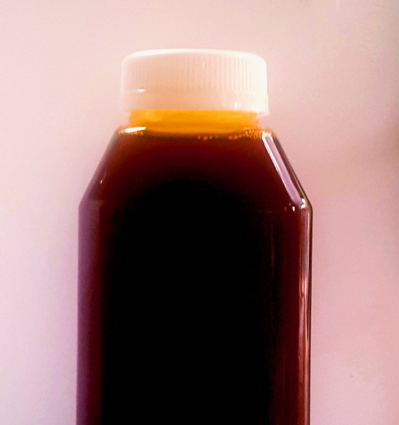 May include: A clear glass bottle with a white lid filled with a dark brown liquid. The liquid has a slight orange hue at the top.