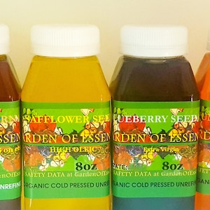 May include: Four 8-ounce bottles of organic oil, labeled with different seed types: Sea Buckthorn, Safflower, Blueberry, and Pumpkin. Each bottle has a green label with a colorful illustration of the seed and the words "Garden of Essences".