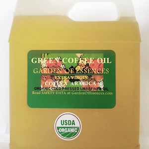 May include: A large, yellow-tinted plastic jug of green coffee oil. The label reads "Green Coffee Oil, Garden of Essences, Extra Virgin Coffea Arabica, Organic Cold Pressed Unrefined Oil." A USDA Organic seal is also visible.