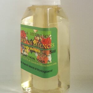 May include: A clear glass bottle with a white cap, containing a yellow liquid. The label reads "Vanilla Planifolia Hydrosol, Garden of Essences, Organic Facial Toner, 8 oz, TY DATA at GardenOfEssences.com, RY: French Island of Madagascar".