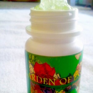 May include: A white plastic bottle with a green label that says "Garden of Ess" and a floral design. The bottle is open and filled with a green gel.