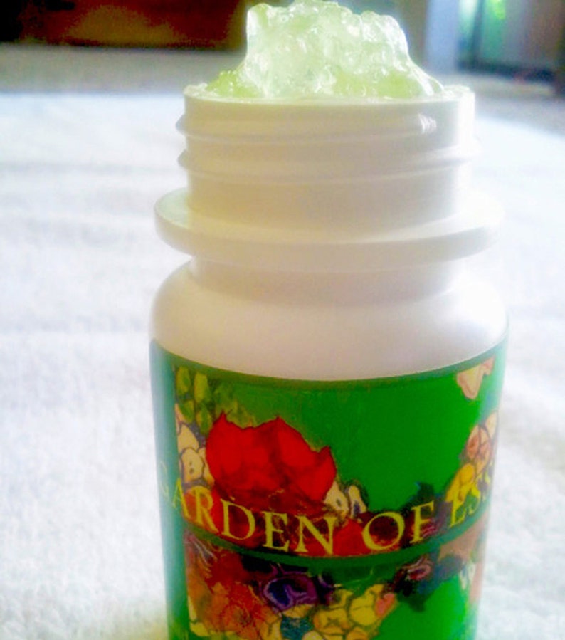 May include: A white plastic bottle with a green label that says "Garden of Ess" and a floral design. The bottle is open and filled with a green gel.
