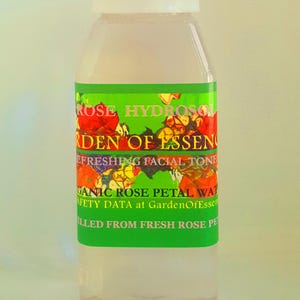 K&ouml;nnte beinhalten: Eine durchsichtige Glasflasche mit wei&szlig;em Verschluss, gef&uuml;llt mit einer hellrosa Fl&uuml;ssigkeit. Das Etikett ist gr&uuml;n mit einem floralen Design und dem Text "ROSE HYDROSOL GARDEN OF ESSENCE REFRESHING FACIAL TONE ORGANIC ROSE PETAL WATER SAFETY DATA at GardenOfEssence FILLED FROM FRESH ROSE PETALS".