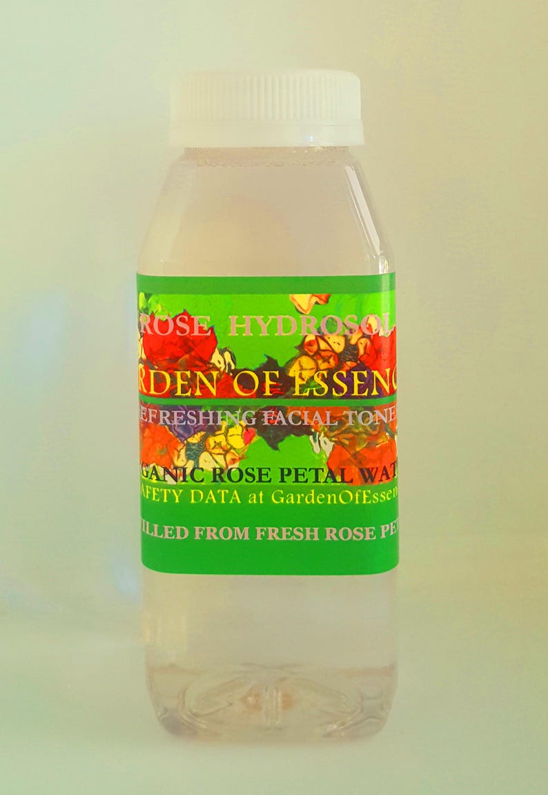 K&ouml;nnte beinhalten: Eine durchsichtige Glasflasche mit wei&szlig;em Verschluss, gef&uuml;llt mit einer hellrosa Fl&uuml;ssigkeit. Das Etikett ist gr&uuml;n mit einem floralen Design und dem Text "ROSE HYDROSOL GARDEN OF ESSENCE REFRESHING FACIAL TONE ORGANIC ROSE PETAL WATER SAFETY DATA at GardenOfEssence FILLED FROM FRESH ROSE PETALS".