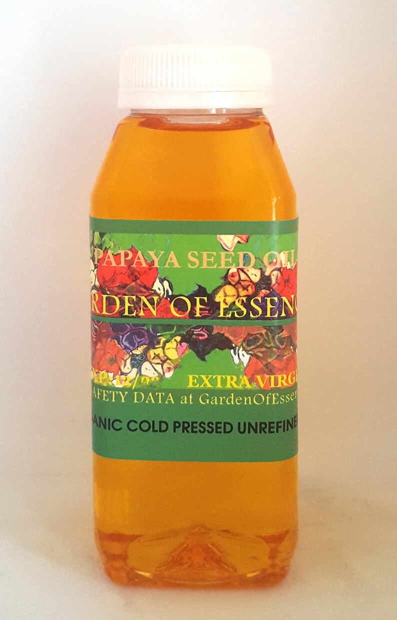 K&ouml;nnte beinhalten: Eine durchsichtige Kunststoffflasche gef&uuml;llt mit gold-orangem Papayasamen&ouml;l, verschlossen mit einem wei&szlig;en Schraubdeckel. Das gr&uuml;ne Etikett tr&auml;gt den Text PAPAYA SEED OIL, GARDEN OF ESSENCE, EXTRA VIRGIN und ORGANIC COLD PRESSED UNREFINED.