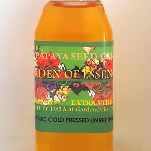 K&ouml;nnte beinhalten: Eine durchsichtige Kunststoffflasche gef&uuml;llt mit gold-orangem Papayasamen&ouml;l, verschlossen mit einem wei&szlig;en Schraubdeckel. Das gr&uuml;ne Etikett tr&auml;gt den Text PAPAYA SEED OIL, GARDEN OF ESSENCE, EXTRA VIRGIN und ORGANIC COLD PRESSED UNREFINED.