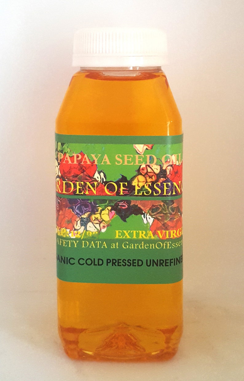 K&ouml;nnte beinhalten: Eine durchsichtige Kunststoffflasche gef&uuml;llt mit gold-orangem Papayasamen&ouml;l, verschlossen mit einem wei&szlig;en Schraubdeckel. Das gr&uuml;ne Etikett tr&auml;gt den Text PAPAYA SEED OIL, GARDEN OF ESSENCE, EXTRA VIRGIN und ORGANIC COLD PRESSED UNREFINED.