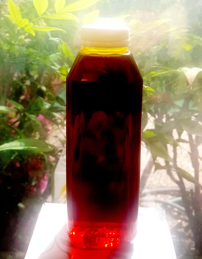 May include: A clear plastic bottle with a white lid filled with a dark red liquid. The bottle is sitting on a white surface.