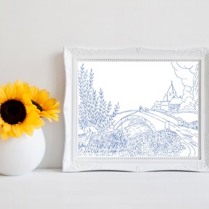 May include: A blue line drawing of a bridge over a river with a small village in the background. The drawing is framed in a white frame.
