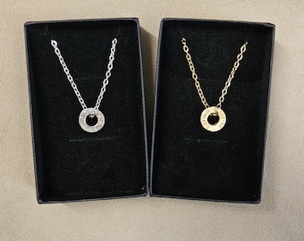May include: Two necklaces in black boxes. One is silver-toned, the other gold-toned. Each necklace features a delicate chain and a circular pendant with engraved text. The pendants are approximately 0.5 inches in diameter.