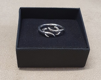 May include: A silver ring featuring a delicate, twig-like design. The ring is presented in a black velvet ring box.