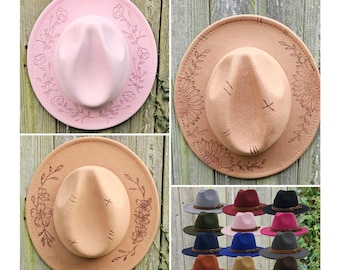 May include: A set of ten felt fedora hats with a variety of colors and designs. The hats have a wide brim and a floral design. The hats are displayed on a wooden surface.