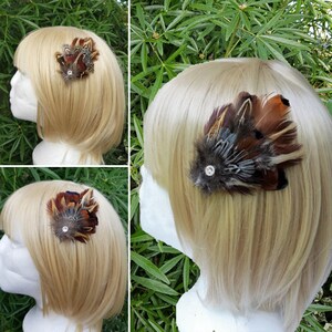 Puede incluir: Tres imágenes de una pinza para el pelo de plumas marrones y grises con un acento de strass. La pinza para el pelo se muestra en un maniquí con cabello rubio.