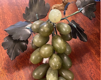 May include: A green jade grape cluster with black jade leaves. The grapes are carved in a realistic style and the leaves are detailed with veins.
