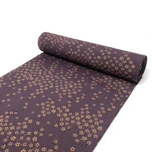 May include: A roll of purple fabric with a repeating pattern of small, light brown flowers. The fabric has a subtle ribbed texture.