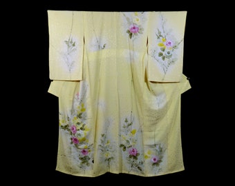 May include: A yellow kimono with a floral pattern of pink and yellow roses and green leaves. The kimono is made of a lightweight fabric and has a traditional Japanese design.