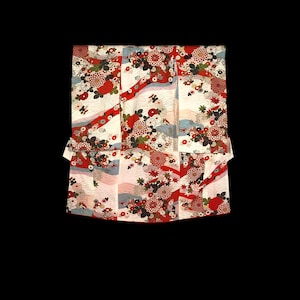 Puede incluir: Un kimono blanco y rojo con un patrón floral. El kimono está hecho de seda y tiene un diseño japonés tradicional.