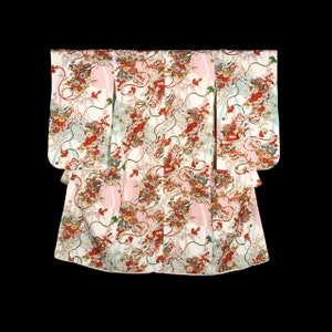 Puede incluir: Un kimono blanco con un patrón floral en tonos de rosa, rojo y azul. El kimono está decorado con intrincados diseños de flores, hojas y cintas.