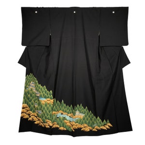 May include: A black kimono with a landscape design. The lower portion features a detailed illustration of a mountain scene with green trees, gold foliage, and buildings. The kimono has wide sleeves and a simple, elegant design.